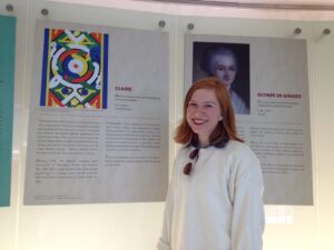 Claire stands in front of panels from the UN Women and Slavery exhibition. 
